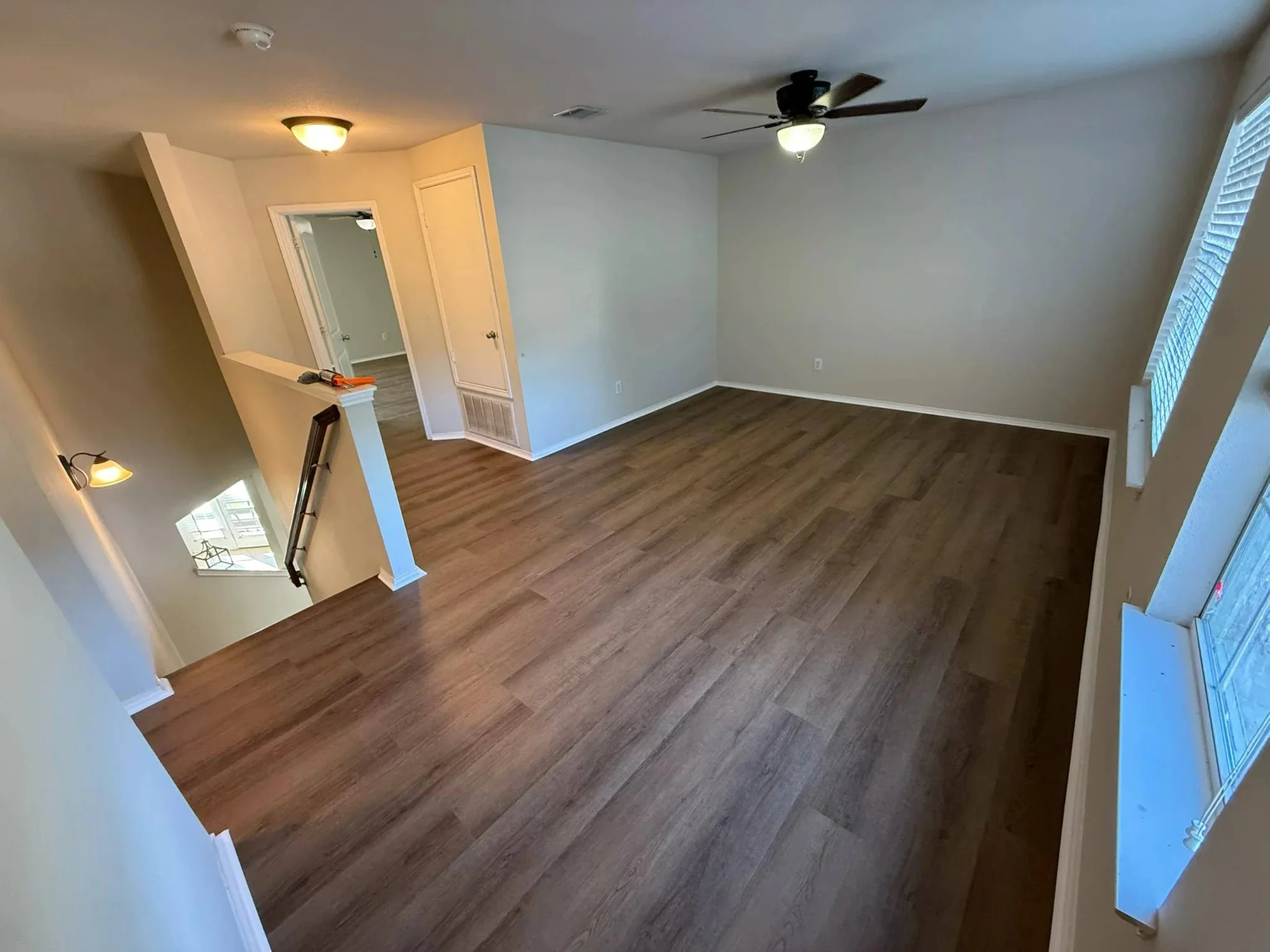 Large bonus room with dark plank flooring and ceiling fan