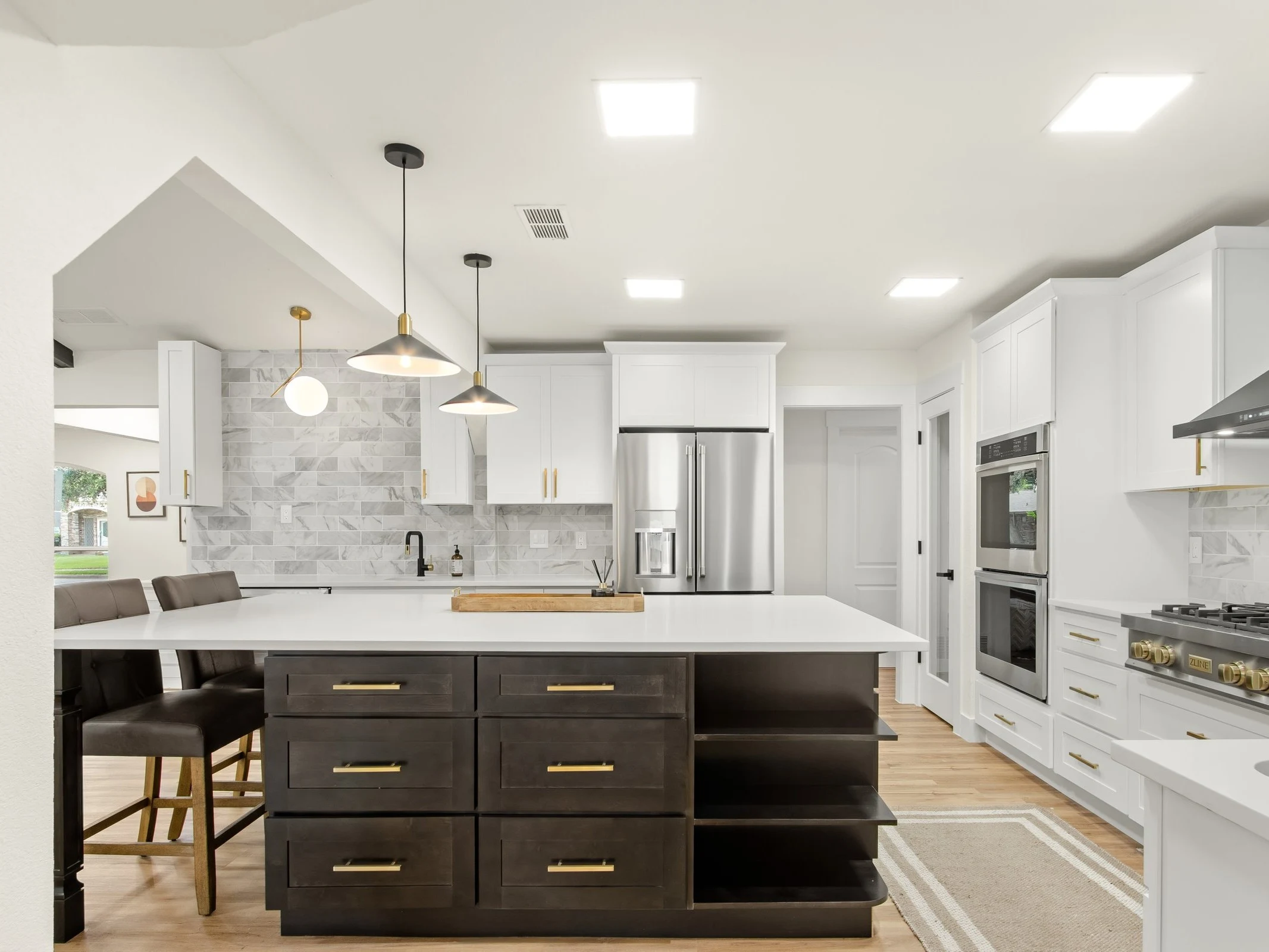 White shaker upper cabinets with dark espresso island and brass hardware